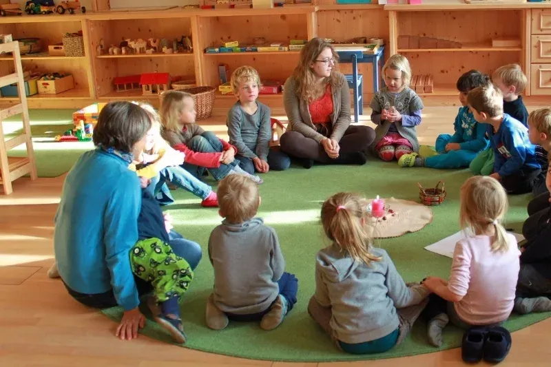 Pädagoginnen und Kinder sitzen in einem gemeinsamen Kreis