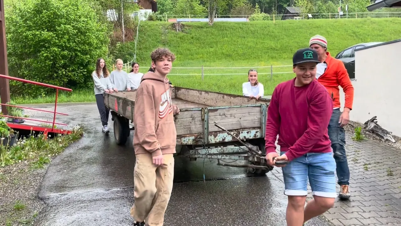 Schülerinnen und Schüler bewegen gemeinsam den alten Anhänger für ihr Bauwagenprojekt